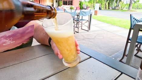 beer being poured into a glass on a patio.