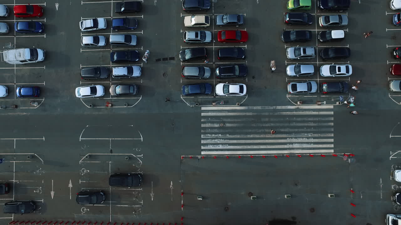 Drone footage people moving with trolleys. Birds eye view car leaving parking