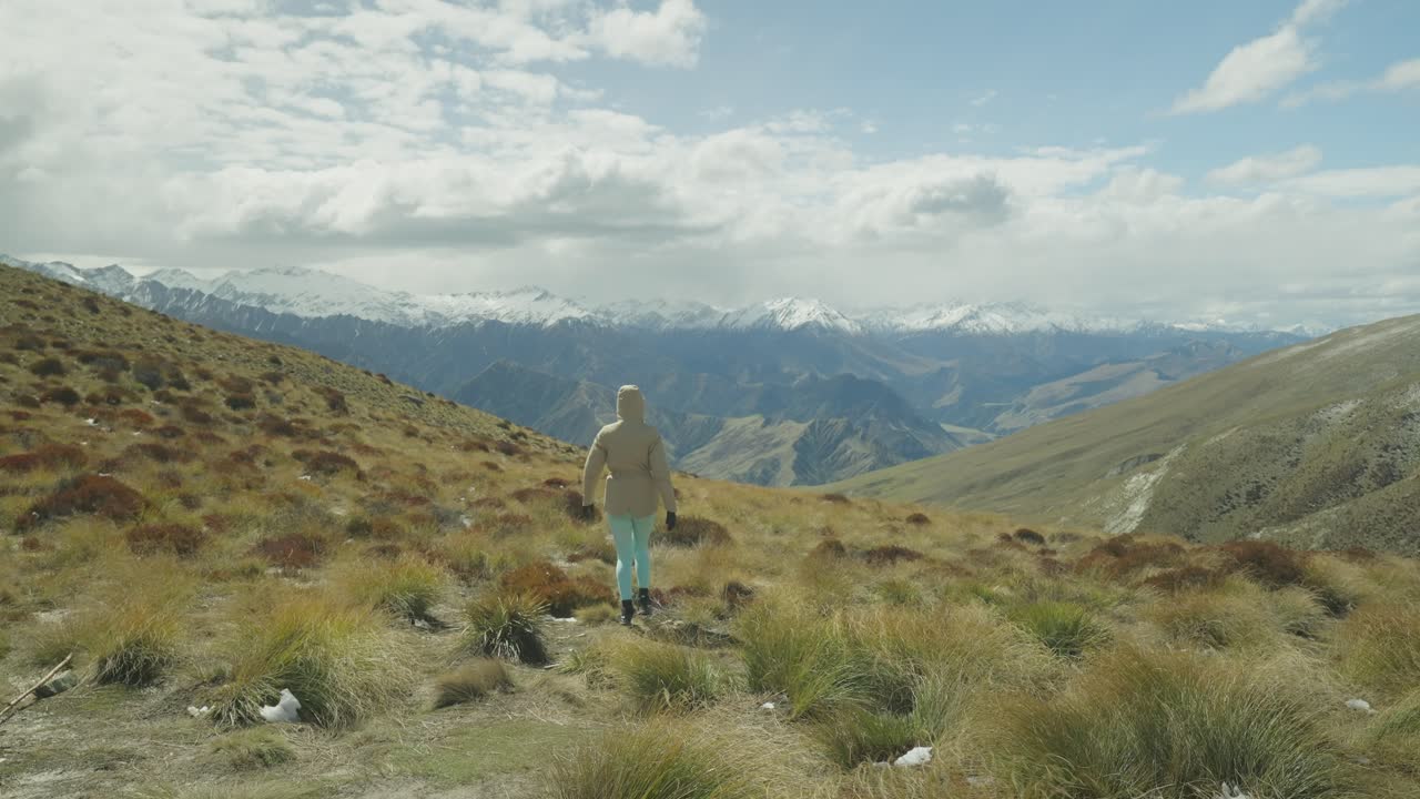 mujer caminando por el campo de matas alpinas en lo alto de las montañas, nueva zelanda