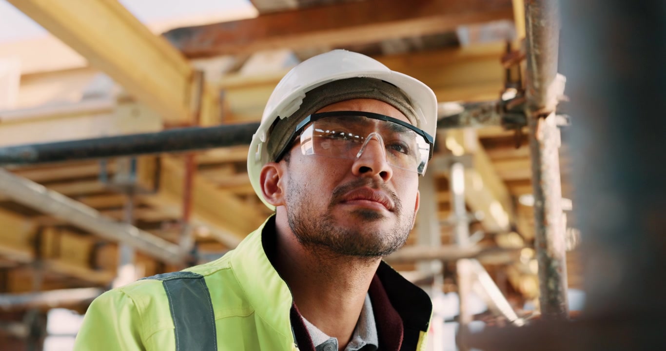 Construction Worker Wearing Safety Gear Looking Up at Building Site
