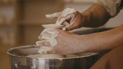pottery artist shaping a clay vessel on a wheel