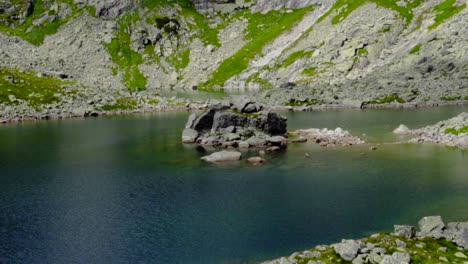 Hermoso-Pequeño-Lago-Azul-De-Montaña-Con-Una-Gran-Isla-Rocosa-Y-Un-Paisaje-Rocoso