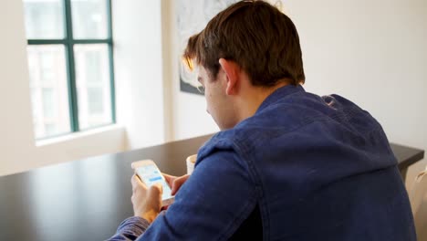 Mann-Benutzt-Mobiltelefon-Mit-Schwarzem-Kaffee-Auf-Dem-Tisch