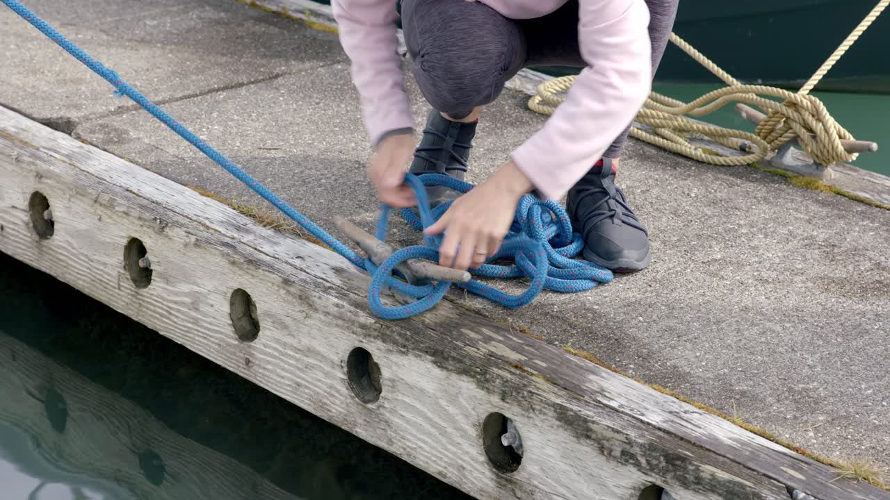 primer plano de manos femeninas desatando barcos nudo de cuerda de amarre en el muelle del puerto, concepto de navegación