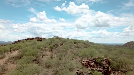 drone en movimiento hacia adelante disparado sobre una montaña en una granja de caza seca cerca de okahandja, namibia, mostrando el vasto paisaje