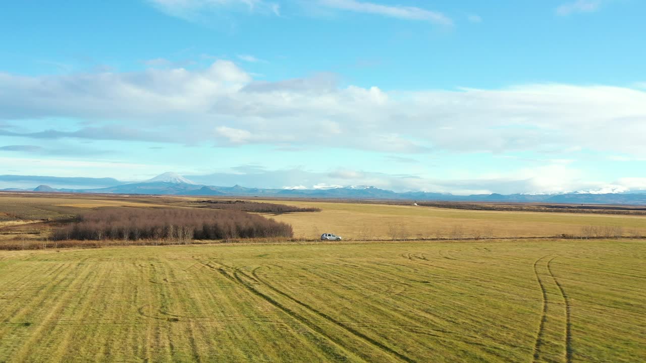 Luftbårent pullback følger bil der kører på landevej på islandske marker