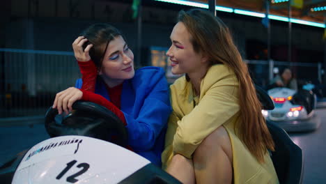 two best friends looking camera hugging at funfair. closeup girls in luna park