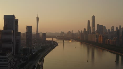 Fliegen-Sie-über-Den-Pearl-River-Mit-Bürogebäuden-In-Der-Innenstadt-Am-Ufer-Des-Flusses-Bei-Einem-Wunderschönen-Farbenfrohen-Goldenen-Sonnenuntergang