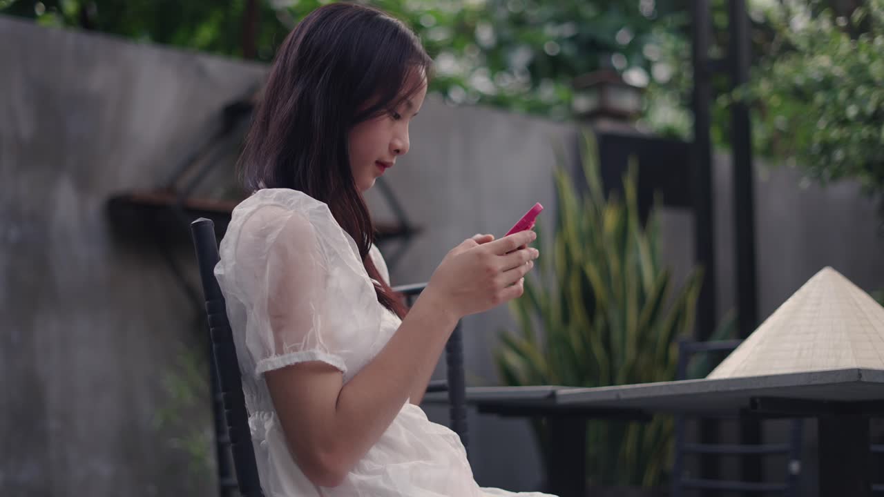 야외 카페에서 스마트폰을 사용하는 여성