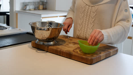 mujer cortando un vegetal con un cuchillo en la encimera de la cocina