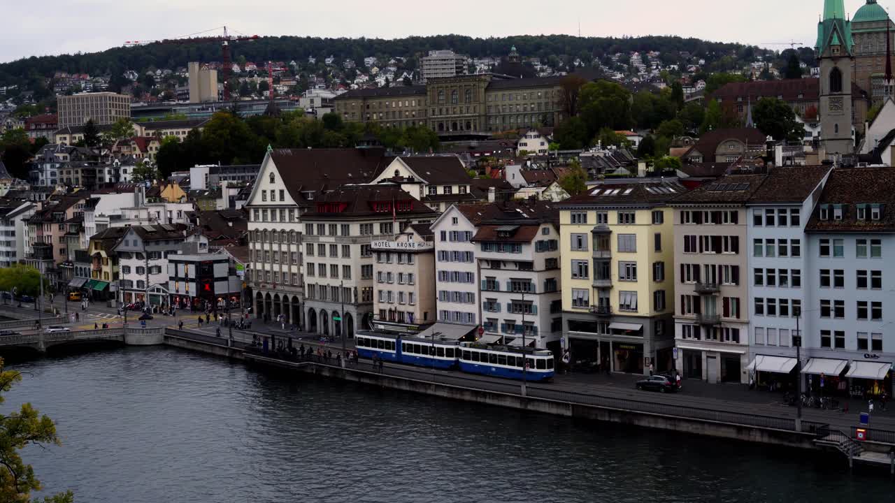 Tram train in Zurich going by next to river Limmat, old town houses in the background