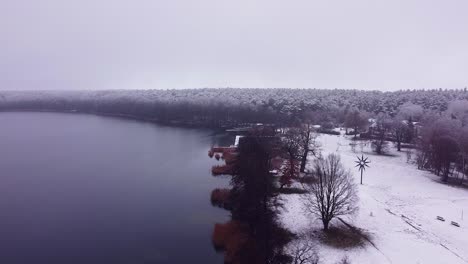 flying from above the shore covered with a thin layer of snow over a calm lake