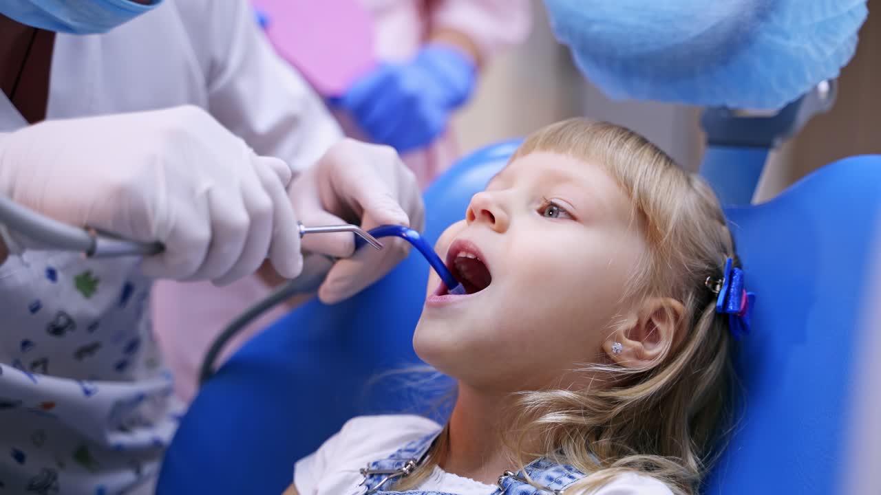 Little child in stomatology chair - close up. Cute blonde girl opened her mouth for teeth check up. Health concept video.