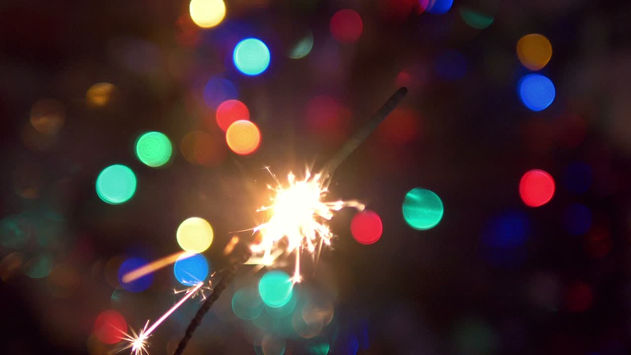 fuoco di bengala ardente e scintille sullo sfondo dell'albero di natale sfocato in 4k slow motion 60fps