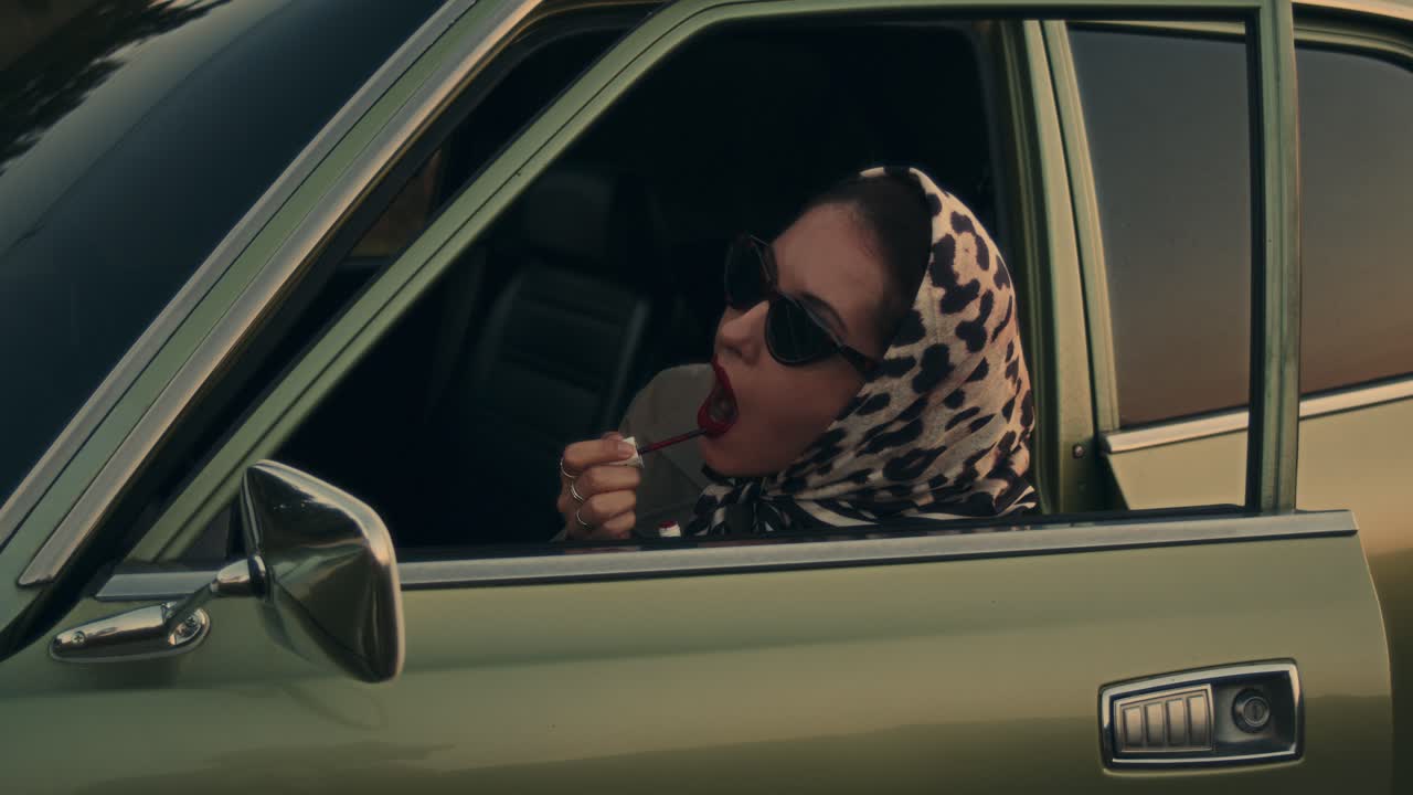 mujer aplicando lápiz labial en un coche de época