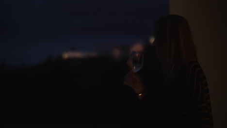 mujer disfrutando del vino en el balcón por la noche