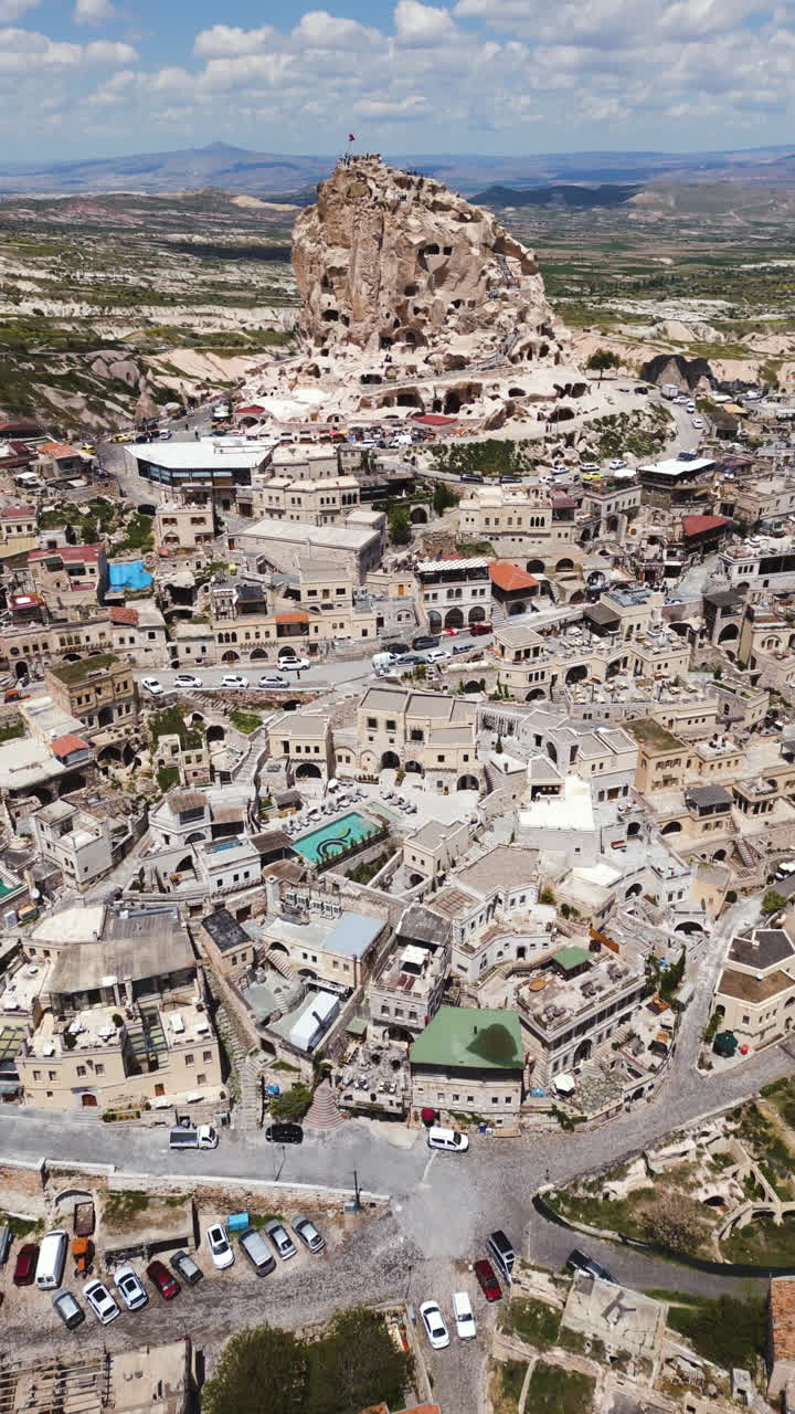 Vertical drone shot tilting toward the Uçhisar Castle, sunny day in Cappadocia