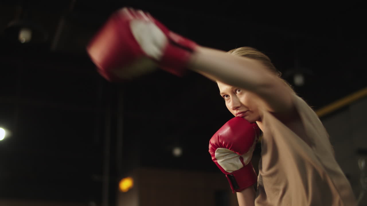 una chica atractiva y en forma boxeando en un gimnasio