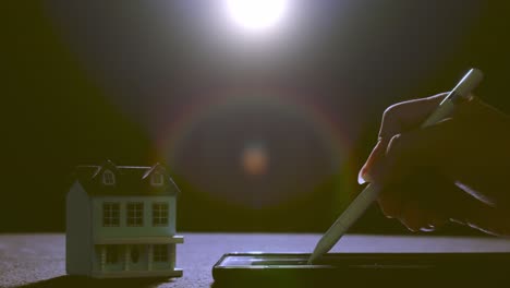 person signs an electronic document for a home loan - isolated view in dark room with a lens flare