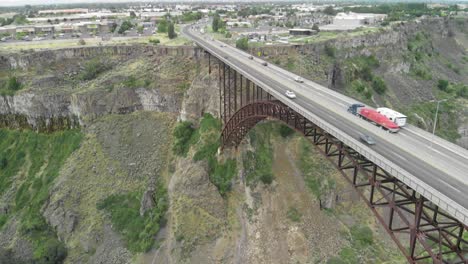 Slow-upward-aerial-tilt-of-vehicles-driving-across-the-Perrine-Memorial-Bridge-above-the-Snake-River-Canyon-in-Twin-Falls,-Idaho-during-the-summer