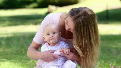 madre feliz sosteniendo a su niña en el parque