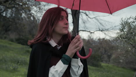 cold woman with red umbrella in the public park on a cloudy day