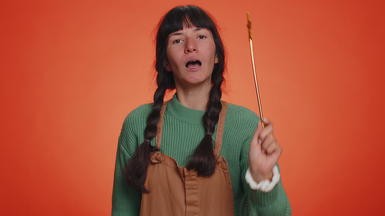 마법사 마법사 젊은 여성이 마법 지 ⁇ 이로 몸짓을 하며 소원을 실현하고 마법사 주문을 던집니다.