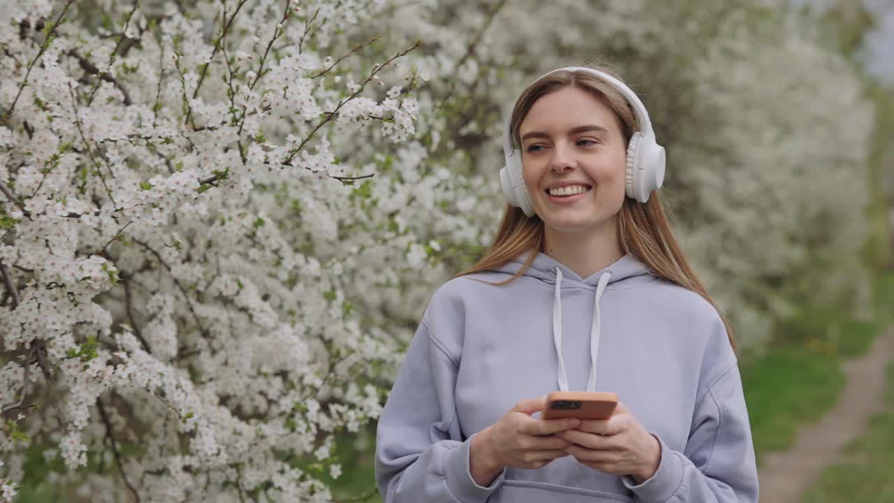 Woman listening to music and using phone in a spring park