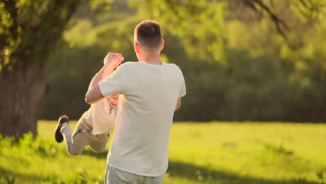 Liebevoller-Junger-Vater-Und-Sohn-Spielen-Im-Sommer-Bei-Sonnenuntergang-In-Zeitlupe-Auf-Dem-Gras.