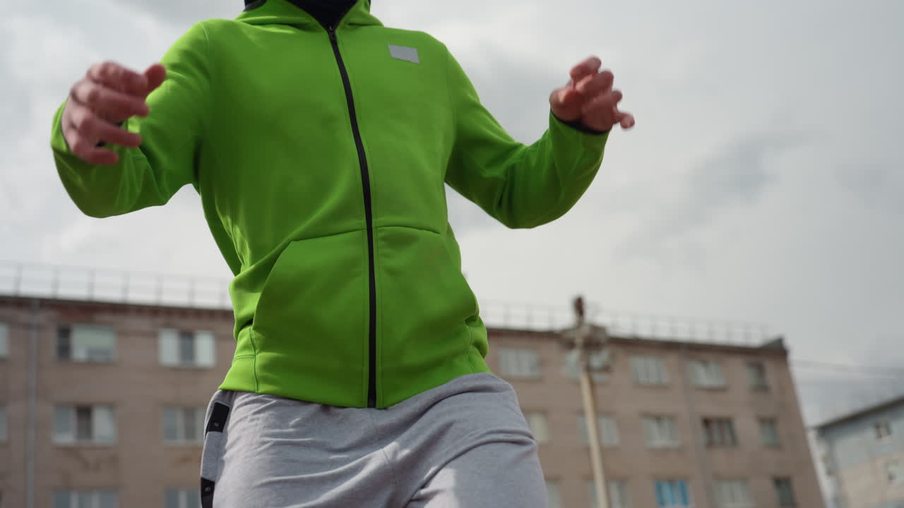 도시 축구 선수가 정확한 기술을 연마하고 있으며, 백인 운동선수가 발과 가슴 터치에 집중하고, 녹색 후드티를 입은 개인이 도시 경기장에서 세밀한 가슴 및 발 컨트롤을 실행하고 있어요.