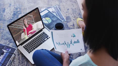 African-american-woman-holding-a-document-having-a-video-call-on-laptop-at-home