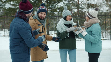 friends enjoying coffee at an ice rink in winter