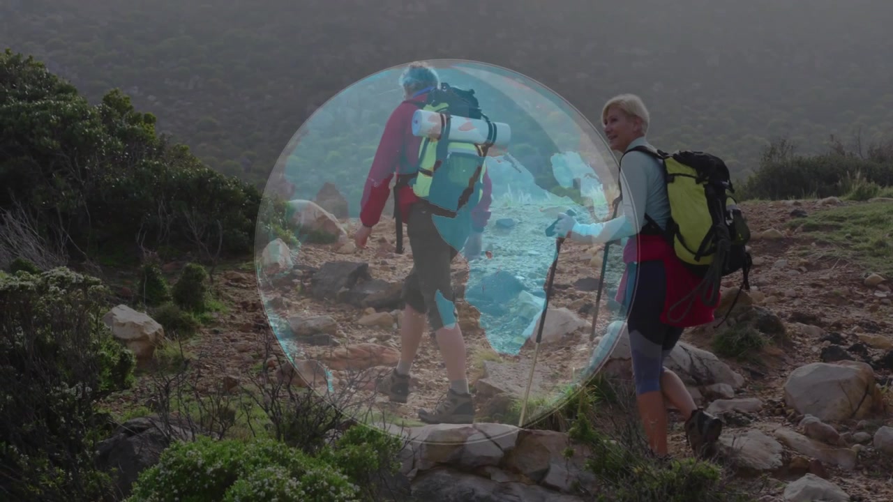 Coppia che fa escursioni su un sentiero di montagna con sovrapposizione digitale di una mappa globale.