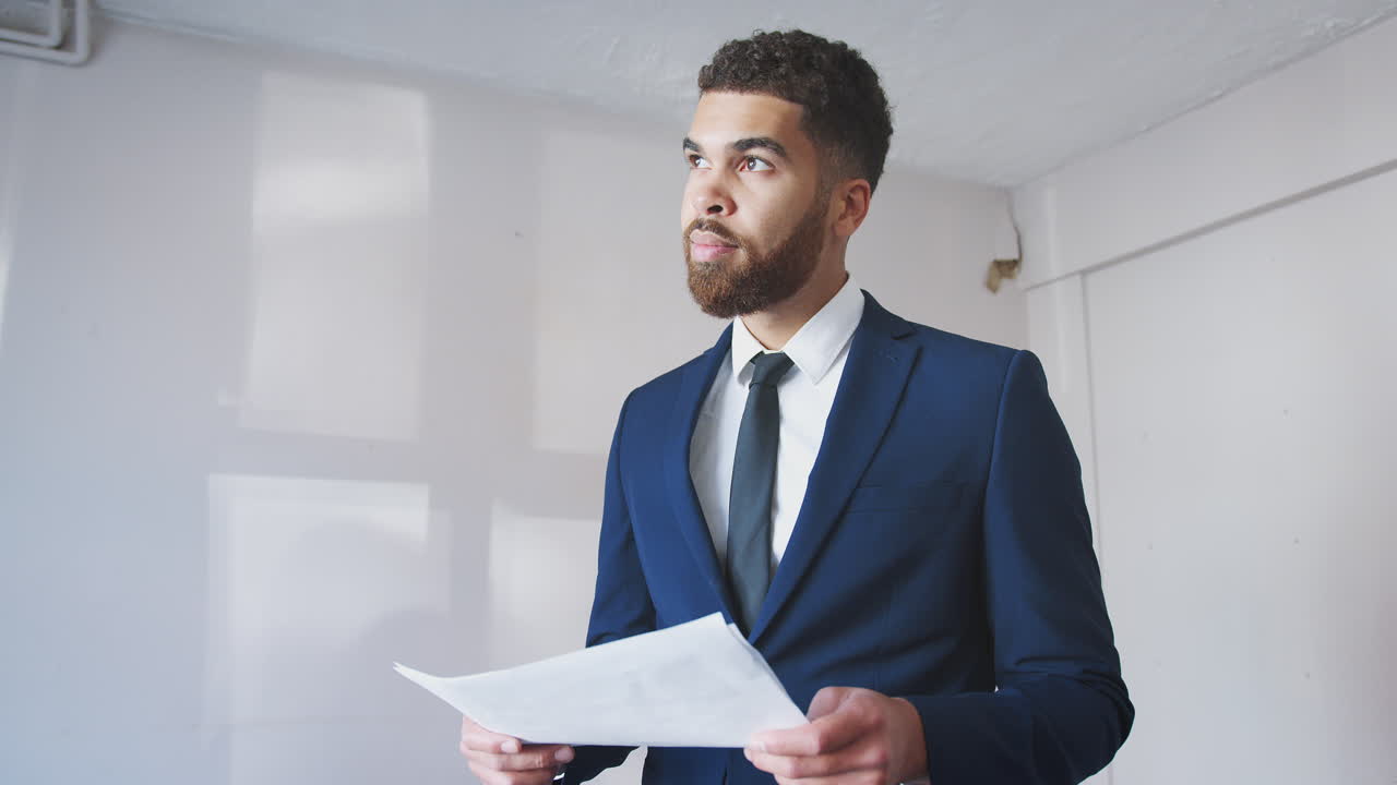 agente inmobiliario masculino que tiene el plano del piso que realiza la valoración de la casa para la venta