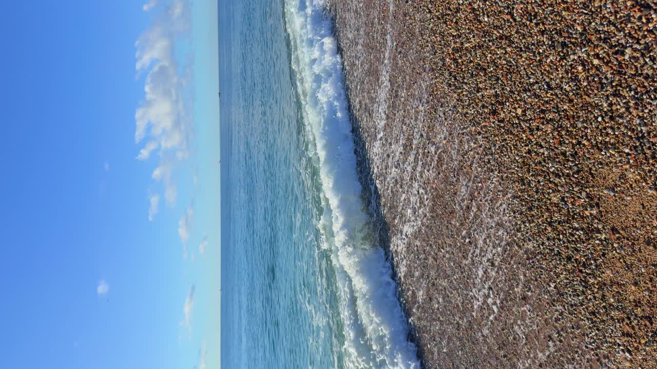 Walking along a beach of small pebbles without people alone with white foam in the foreground copies Space, vertical plane
