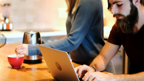 hombre usando computadora portátil mientras la mujer prepara café 4k