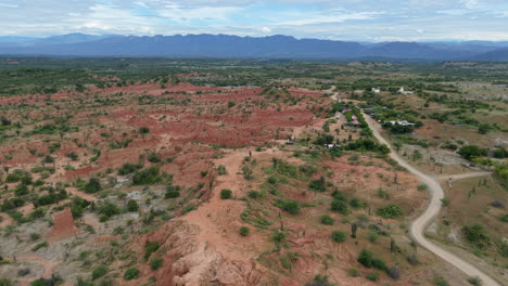 Drone video capturing sweeping views of Tatacoa Desert's vibrant red terrain and unique rock formations under a clear sky, offering a breathtaking natural spectacle.
