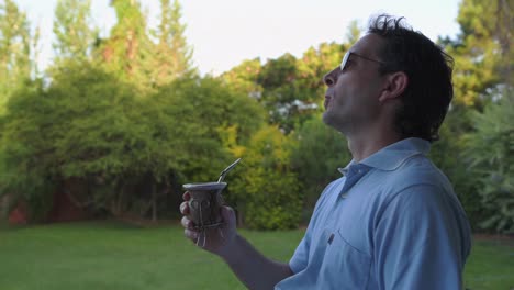 man drinking mate and relaxing in garden of his house with traditional argentina drink