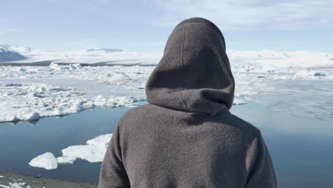 joven viajero rubio parado en la laguna glacial en islandia