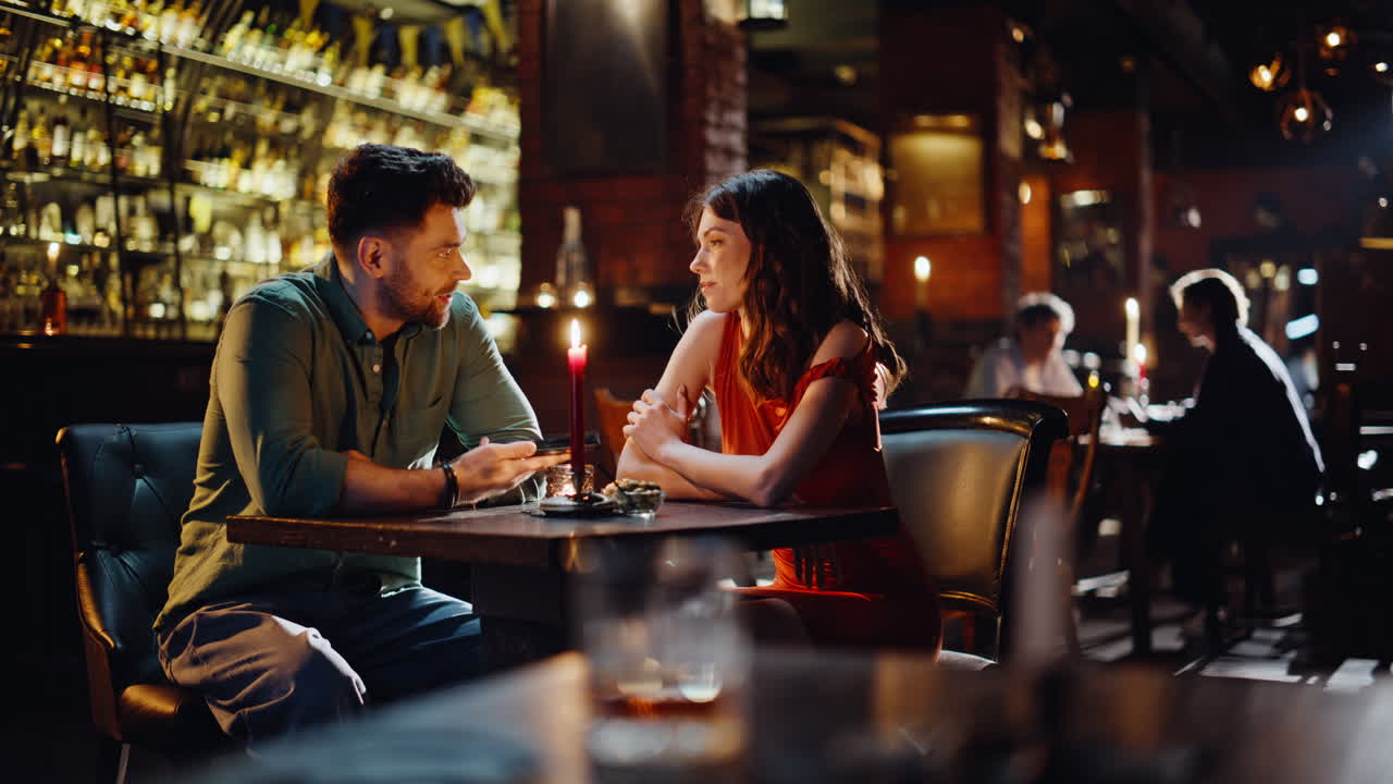 Coppia romantica seduta al bar che parla e sorride. Coppia innamorata che discute.