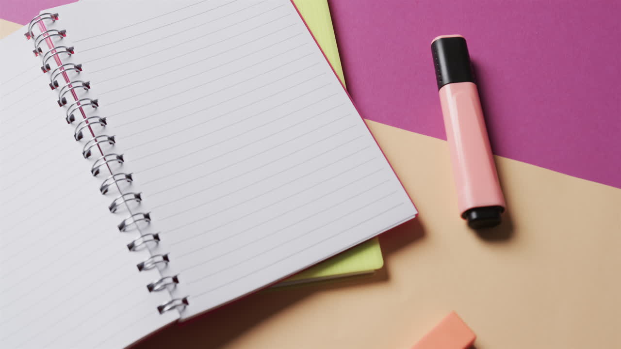Close up of open notebook with school stationery on beige and purple background, in slow motion