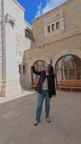 woman taking selfie in front of stone building