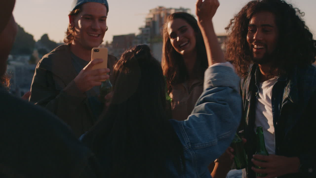 donna di razza mista che balla gruppo di amici diversi che si divertono a fare festa sul tetto a ballare musica al tramonto a bere a divertirsi nel fine settimana a riunirsi