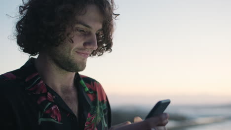 teléfono, amanecer de la playa y el hombre escribiendo un mensaje en línea a
