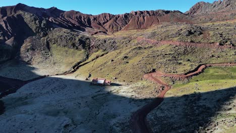 drone video of a remote lodge from andean loges, near vinicunca perus rainbow mountain. the logde is located between mountains surrounding with frost in the morning sun