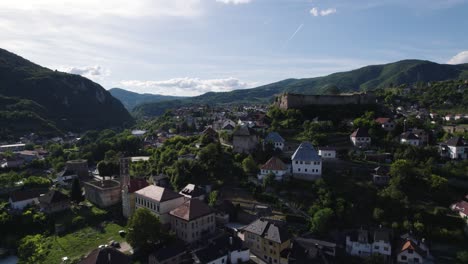aerial view circling jajce hilltop fortress in the lush hills overlooking the old city under bosnia mountain skyline