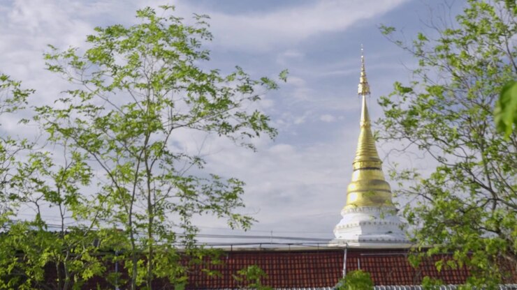 Gylden stupa fra et thailandsk tempel, der titter frem mellem beboelsesejendomme