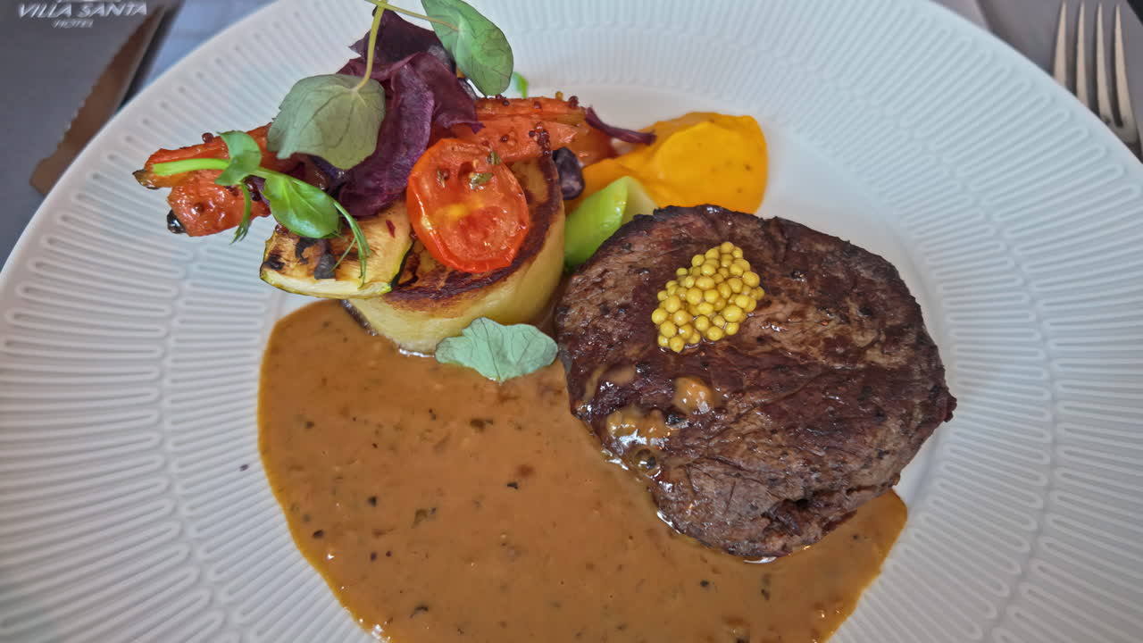 Gourmet steak dinner with whole grain mustard, vegetables, and sauce