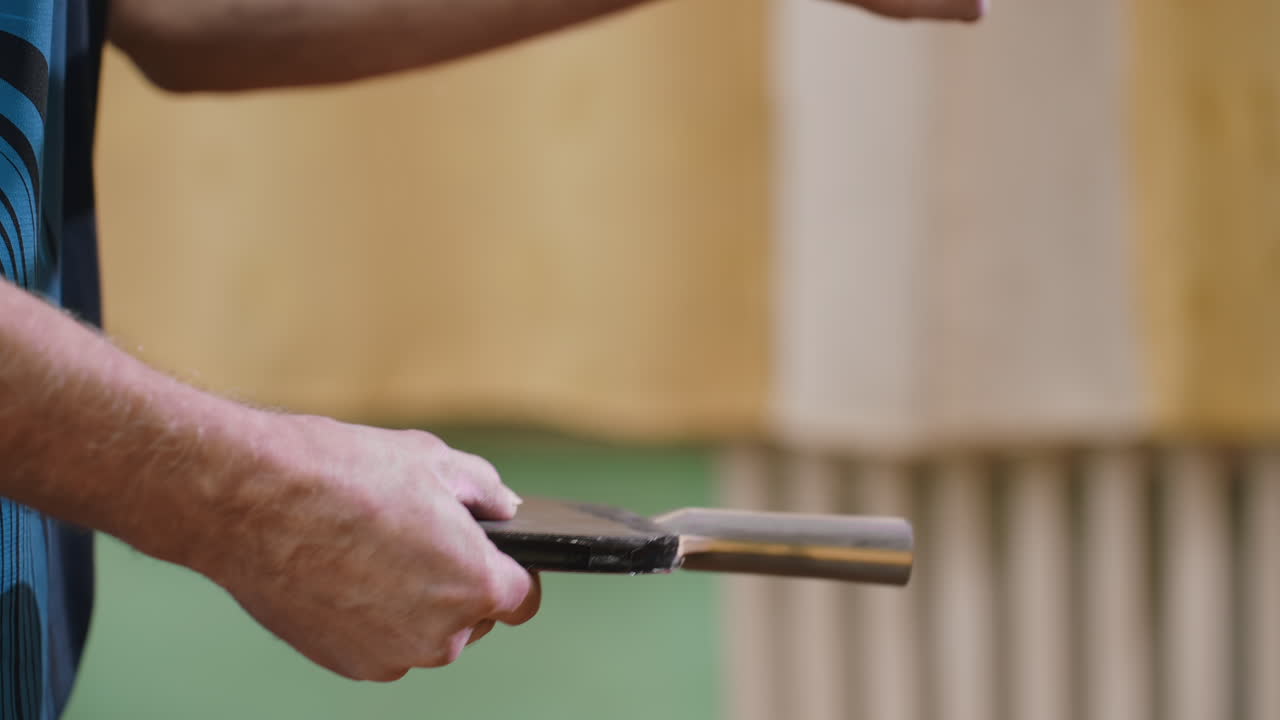 Close up of senior player demonstrating unique technique using racket handle to play tennis indoors, focusing on grip, control, and coordination while practicing precision