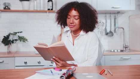 woman reading a book in a kitchen